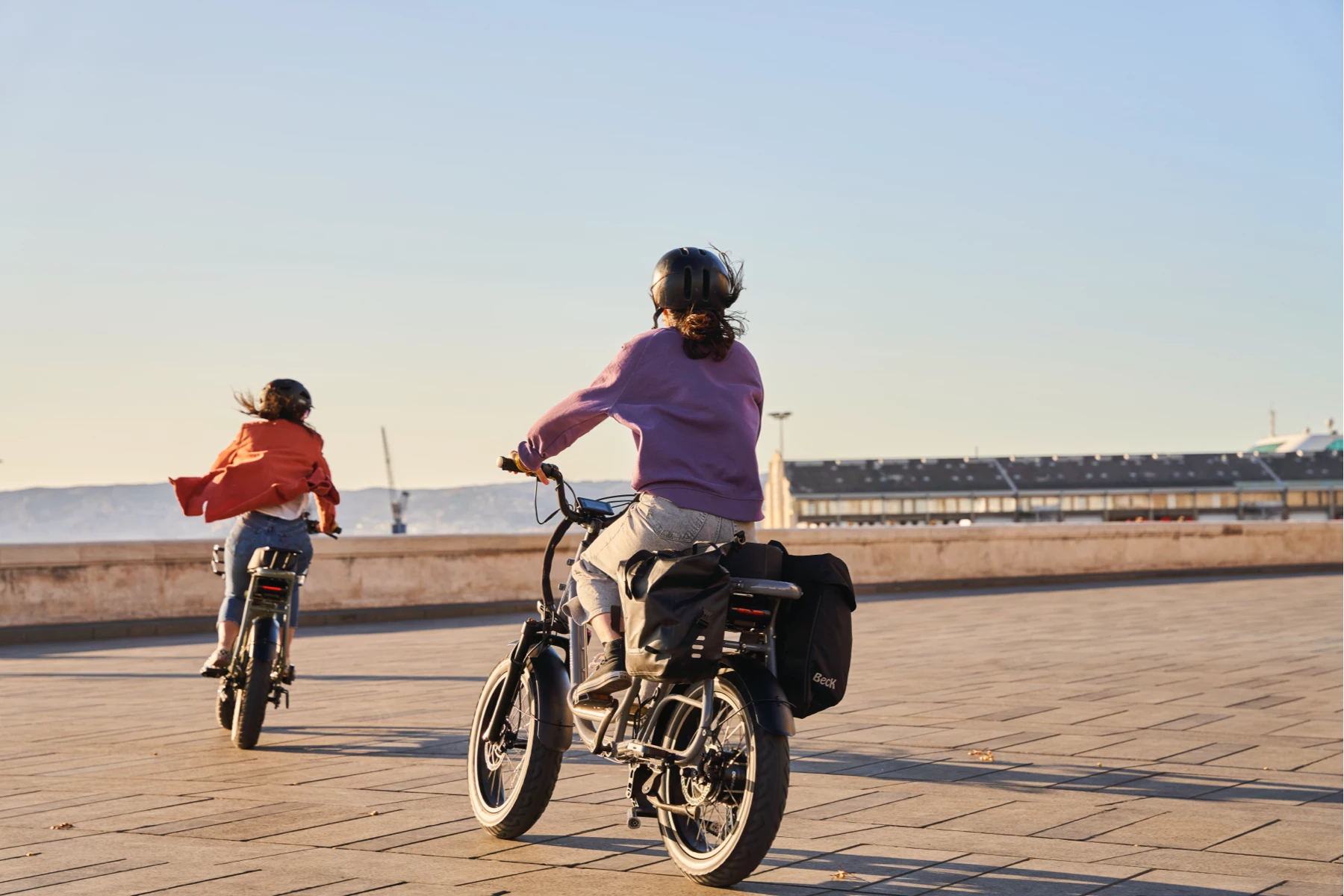 deux femmes en train de rouler sur leurs vélos électriques Elwing Yuvy 2 avec des sacoches de rangement en bord de mer à Marseille