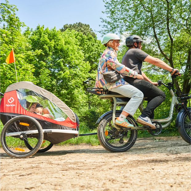 famille couple en train de rouler ensemble sur un vélo électrique biplace yuvy 2 et leurs deux enfants installés dans la remorque