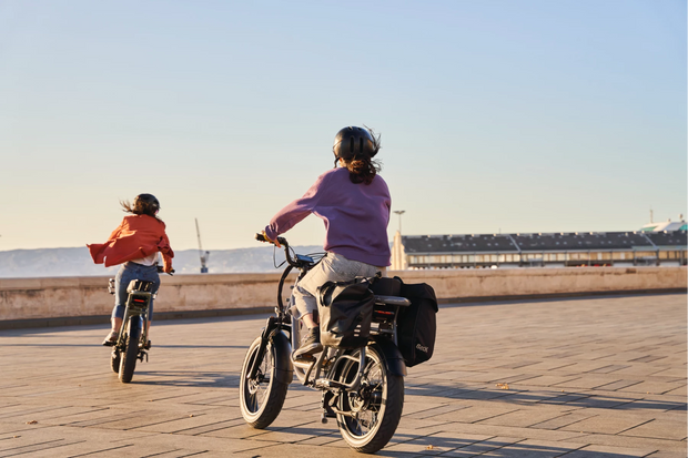 deux femmes en train de rouler sur leurs vélos électriques Elwing Yuvy 2 avec des sacoches de rangement en bord de mer à Marseille